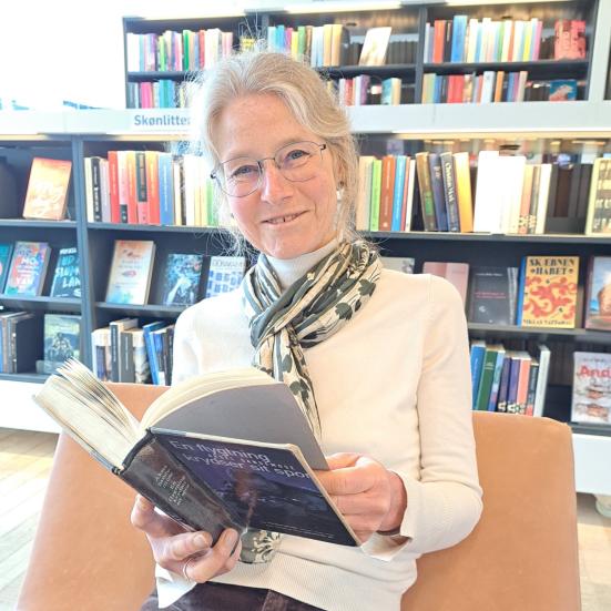 foto af biblioteksfrivillig Bodil Schau med bog og bøger i baggrunden