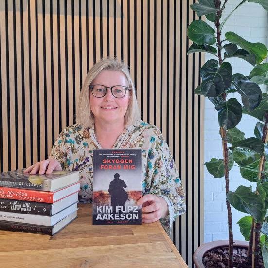 Foto af bibliotekar Annebeth der fremviser en stak bøger ved et bord på Espergærde Bibliotek