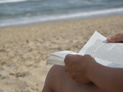 Strand med person der læser en bog