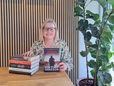 Foto af bibliotekar Annebeth der fremviser en stak bøger ved et bord på Espergærde Bibliotek