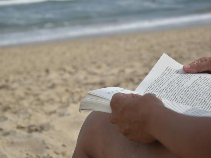 Strand med person der læser en bog