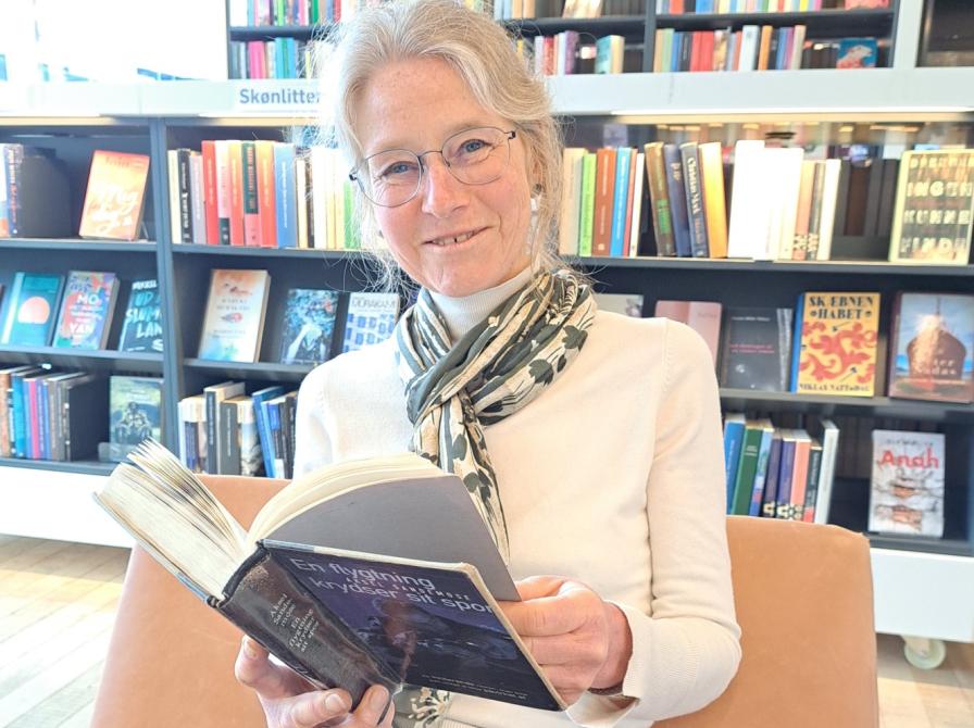 foto af biblioteksfrivillig Bodil Schau med bog og bøger i baggrunden