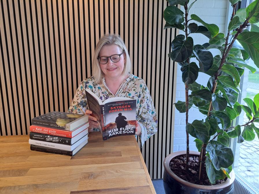 Bibliotekar Annebeth læser bog ved bord på Espergærde Bibliotek.