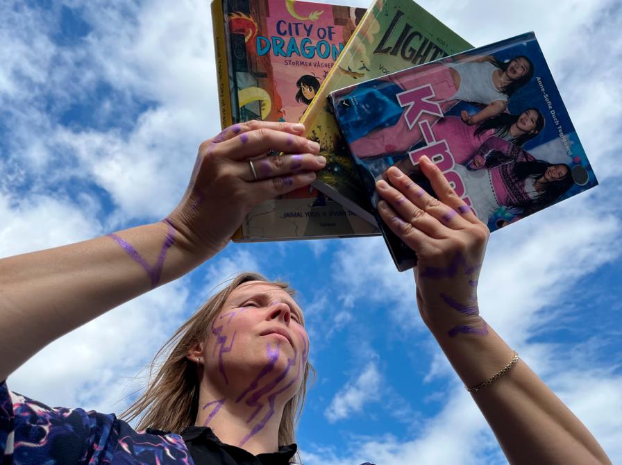 Person malet som en dæmon fra KPOP Demon Hunters holder 3 bøger